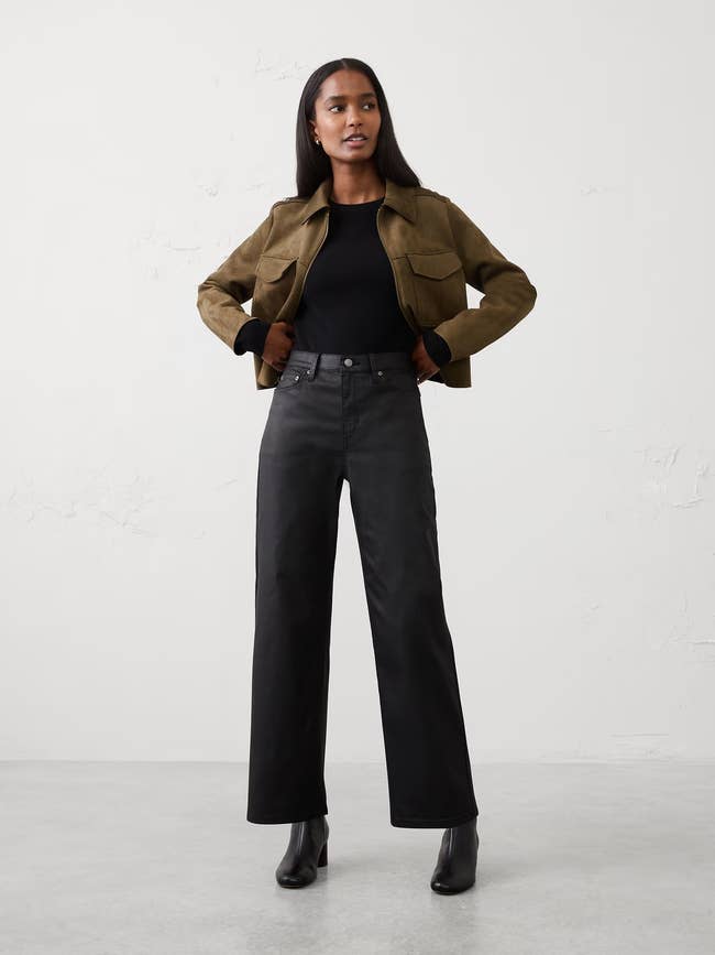 Person wearing a casual outfit with a brownish  jacket, achromatic  top, wide-legged pants, and ankle boots
