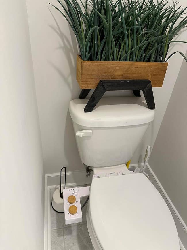 Bathroom country with a toilet that has a tushy bidet attached to it