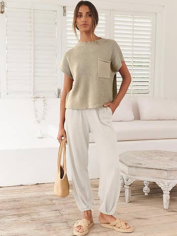 Person in a casual cream knit top and loose white trousers 