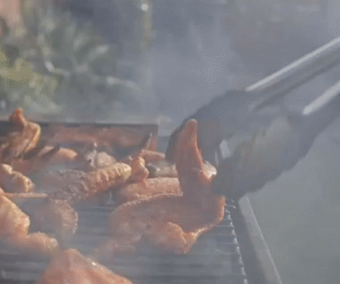 gif of someone using the tongs to flip pieces of chicken on a grill