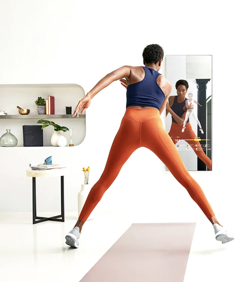 model participates in workout class held in interactive mirror in front of them