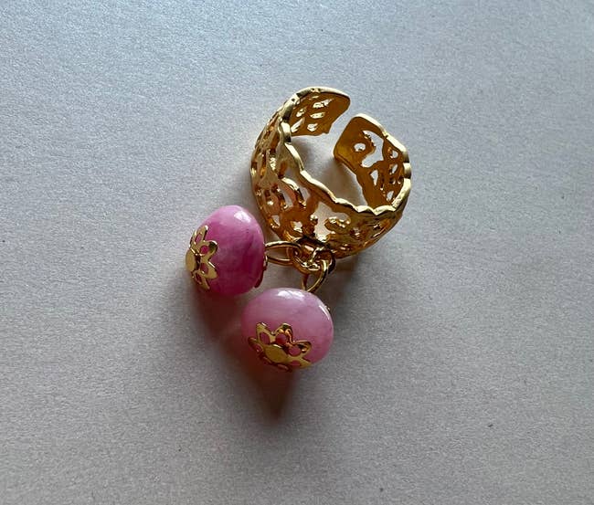 A gold plated ring with two pink stones attached