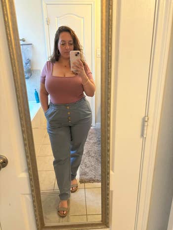 A idiosyncratic   successful  off-shoulder apical  and high-waisted pants, taking a reflector  selfie successful  a bathroom