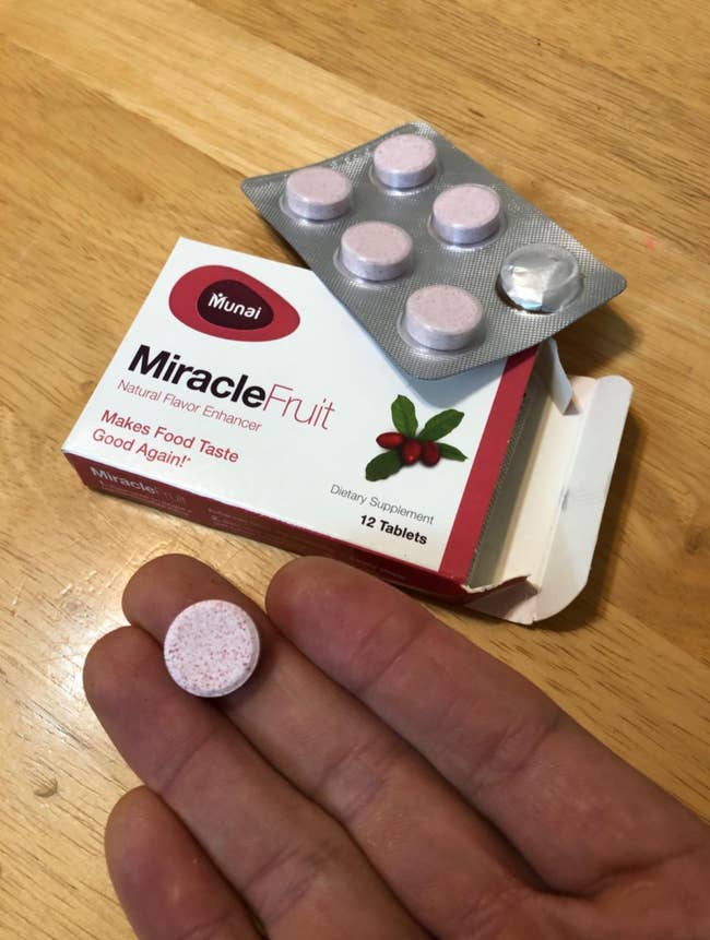 Reviewer holding pink tablet next to box of Miracle Berries 