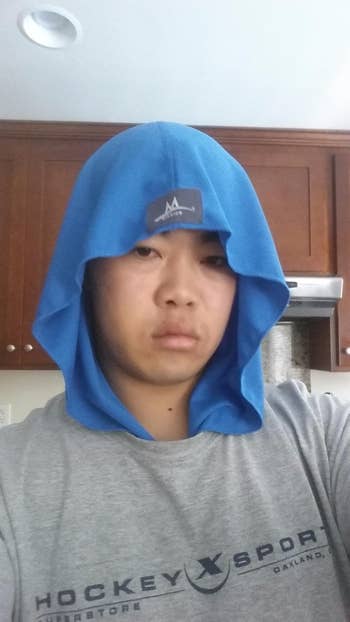 A reviewer wearing the cooling hoodie in blue on their head