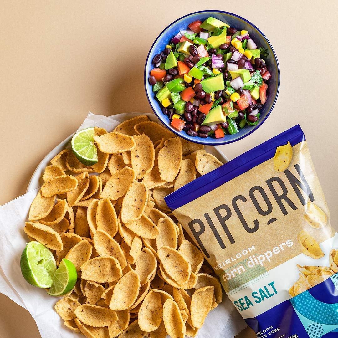 bag of pipcorn sea salt corn dipper chips next to a bowl of salsa