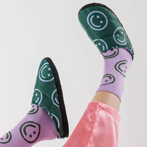 a model wearing the smiley face slippers