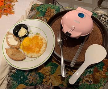 reviewer's tiny (smaller than the plate) pink griddle next to a plate of eggs and toast