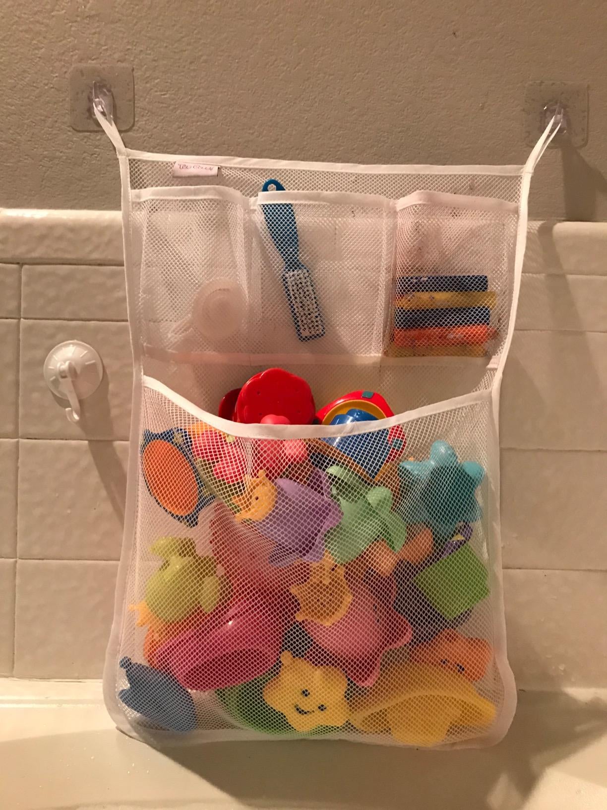 reviewer's photo of a mesh organizer containing bath toys and stuck to the wall
