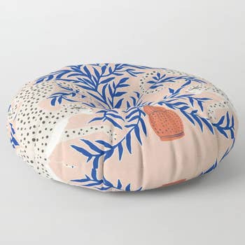 Pink round floor pillow with spotted leopard, blue vines, and coral spotted vase