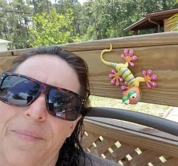 Reviewer next to a colorful gecko attached to a wooden pool deck railing