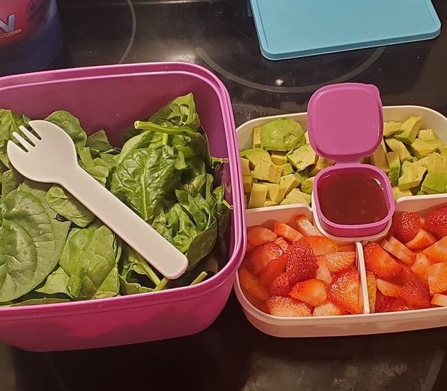 reviewer photo of their unstacked box; there is spinach in the base and then avocado, strawberries, and dressing in the other tray