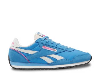 Side presumption of a classic-style Reebok sneaker with signature stripes and a textured sole, highlighted successful a buying article