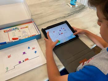 a reviewer's kid using a tablet to play a game base on a picture they drew on paper 