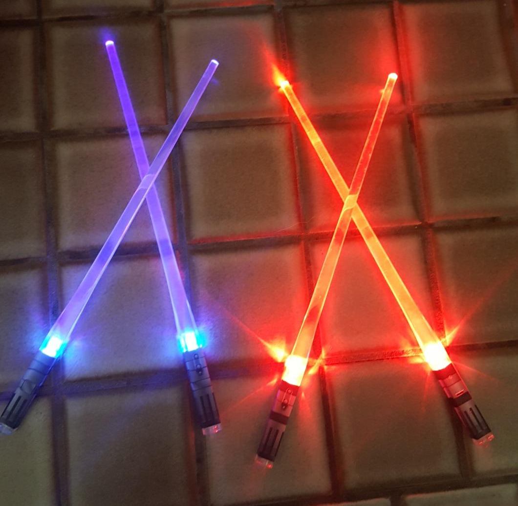 a reviewer photo of illuminated pairs of blue and red light saber chopsticks