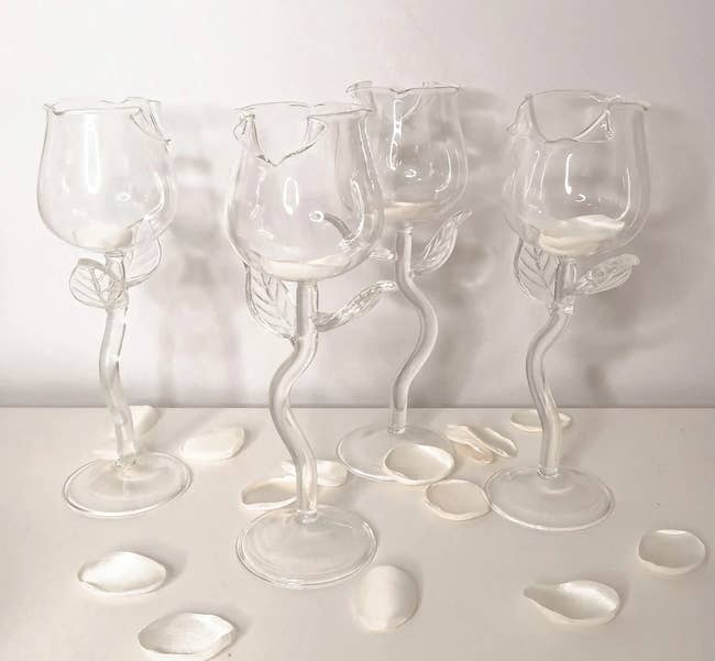 Set of four clear glass rose-shaped glasses on a white table