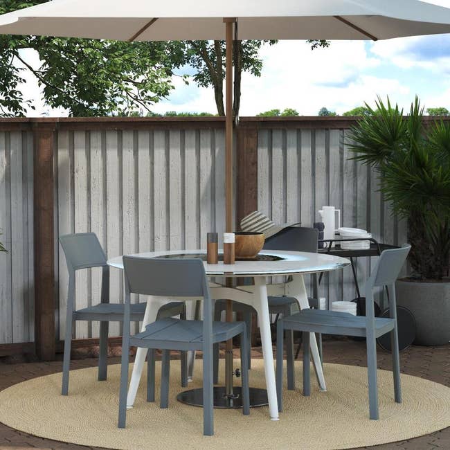 round outdoor able with an umbrella and gray modern looking chairs