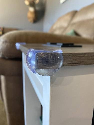 Table country with a transparent information defender attached, adjacent to a couch, demonstrating childproofing location safety