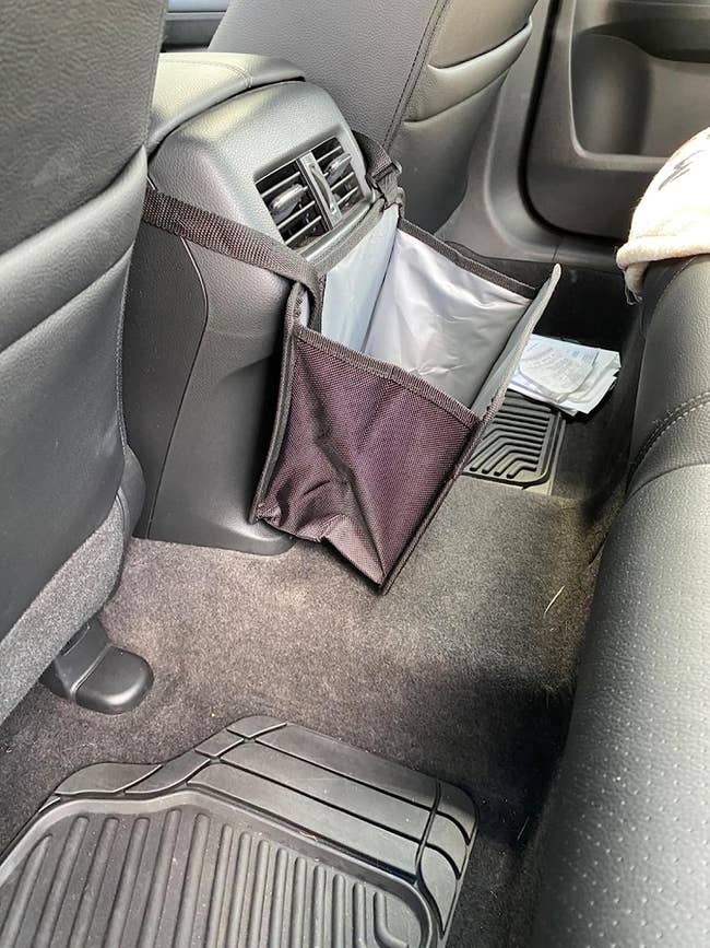 The trash can attached to the center console in the back seat of a vehicle 