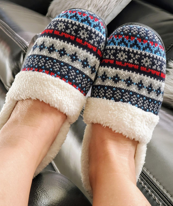 reviewer in blue gray red and black fair isle slippers with fuzzy trim