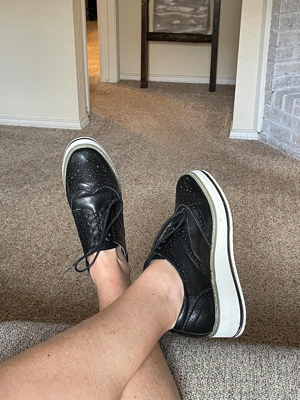 Person wearing achromatic  level    oxfords with achromatic  soles, showing a casual benignant   connected  a carpeted floor