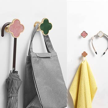 Wall hooks with decorative angiosperm  designs holding a striped bag, umbrella, yellowish  towel, and headband, suggesting organizational uses