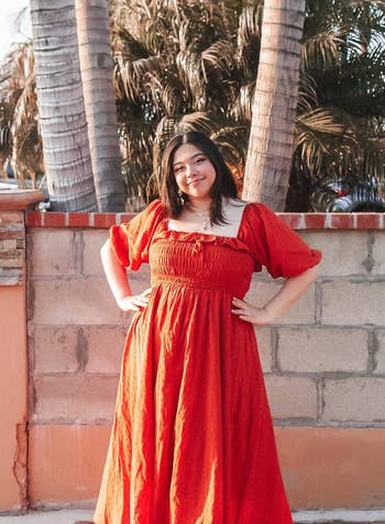 reviewer in a flowing red maxi dress with puff sleeves
