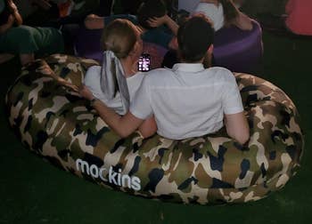 Reviewer image of product in camouflage with couple sitting on top of it outside at night 