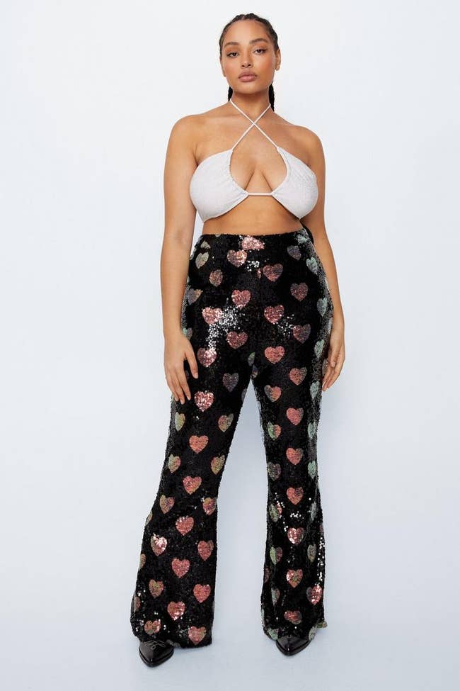 model in high waisted black and metallic heart patterned sequined pants
