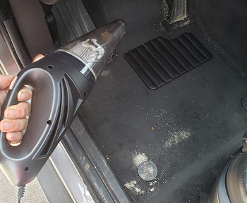before photo of a reviewer holding up the vacuum near a dirty car floor