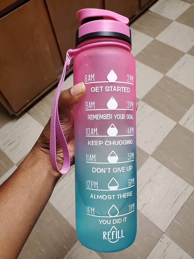 reviewer holding a pink and blue ombre water bottle with motivational messages on it