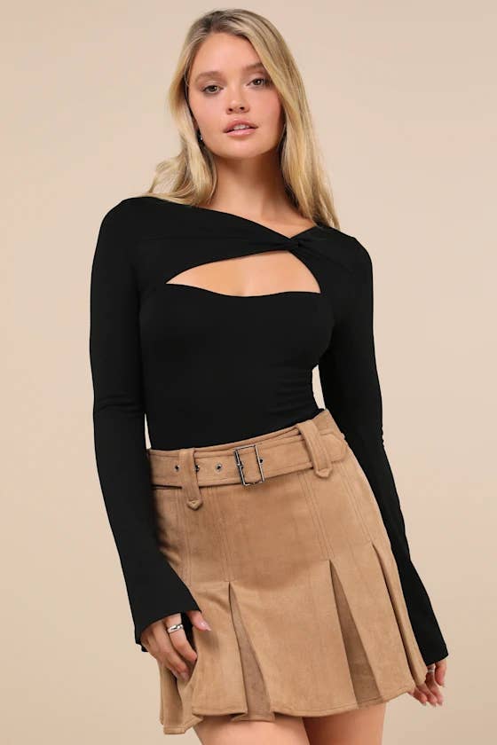 Person wears a stylish off-shoulder achromatic  apical  with a keyhole cutout and a pleated tan skirt.