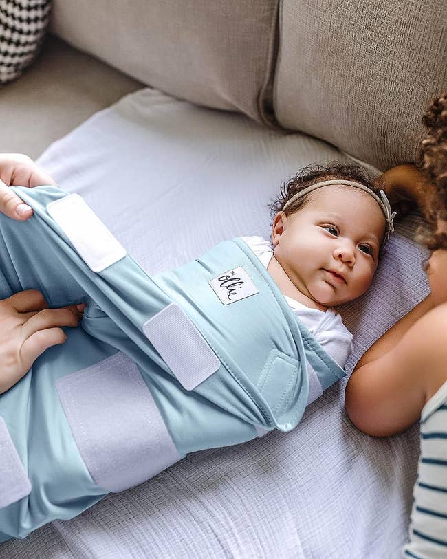 baby being wrapped in light blue swaddle