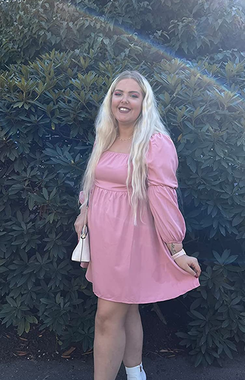 reviewer wearing the pink dress with white boots