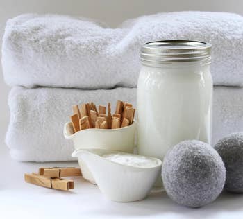 two of the gray dryer balls next to some white towels, clothespins, and soap