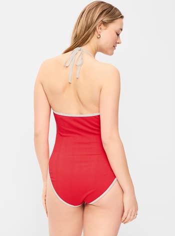Person modeling a one-piece swimsuit with a halter cervix tie, viewed from the back