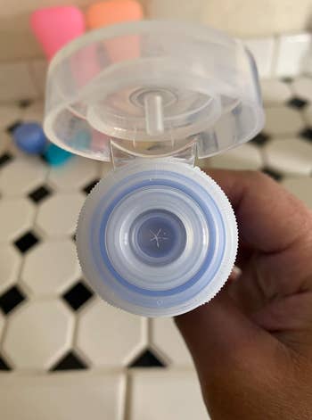 reviewer showing the squeeze tube from the leakproof cap 