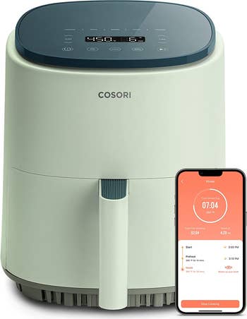 sage green air fryer with a phone open to the Cosori app