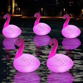the same floating flamingo-shaped lights in a pool at night