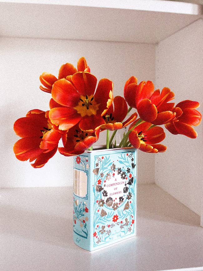 reviewer's book flower vase with orange flowers coming out of it