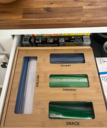 a reviewer photo of the organizer in a drawer with bags poking out of each slot 