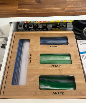 a reviewer photo of the organizer in a drawer with bags poking out of each slot 