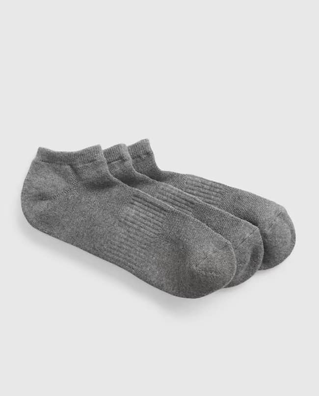 Three grey ankle socks connected a plain background, displayed for buying purposes