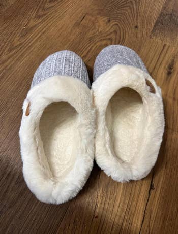 Cozy slip-on slippers with knit and plush detailing connected  a woody  floor, perfect  for indoor comfort