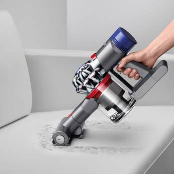 a model using the dyson vacuum to clean a couch