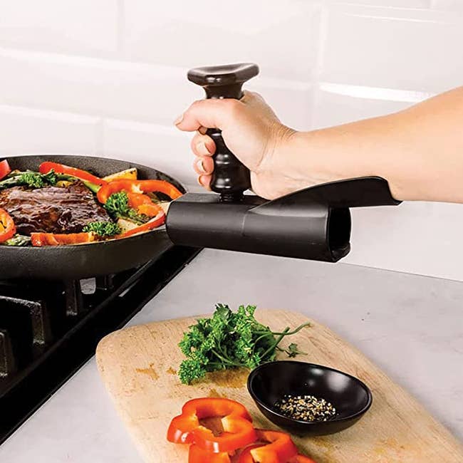 Model holding onto attachment grip on a pan handle that supports their elbow while letting them grab the handle vertically with their fist 