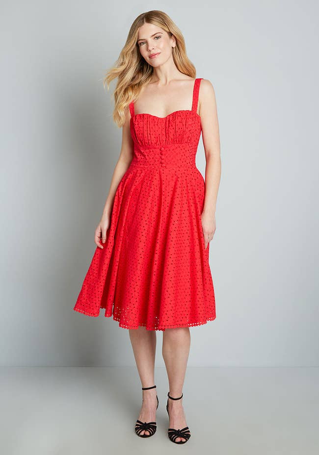 Model wearing the red fit and flare dress with faux button corset on the front