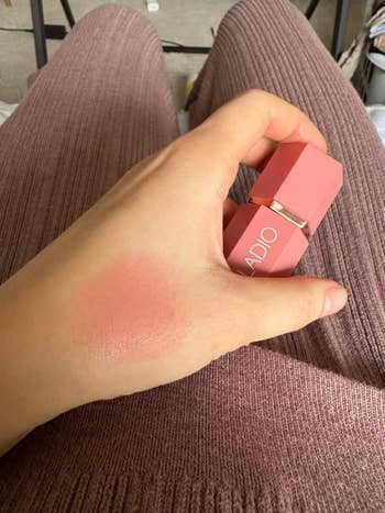 Person's hand with DIOR blush swatch on wrist next to blush container