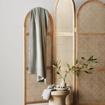 the waffle towel in the color sage hanging over a room divider