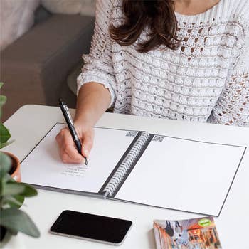 person writing in the normal looking notebook